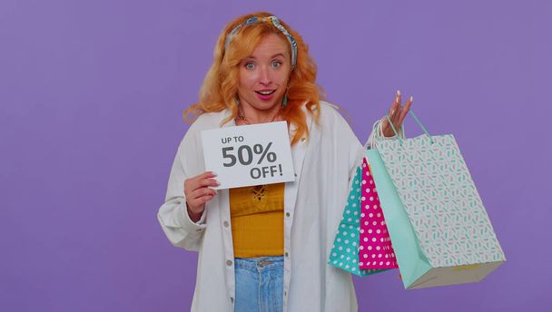 Fröhliches rothaariges Mädchen zeigt Einkaufstüten, Bis zu 50 Prozent Rabatt auf Aufschriften Banner, Black Friday - Foto, Bild