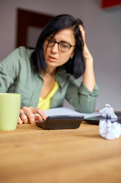Woman accountant sit calculate expenses on calculator at wooden table, modern workplace, freelancer working at home. Female busy manage family budget account expenditures. - Photo, Image