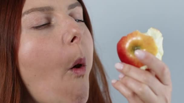 Привлекательная женщина ест спелое красное яблоко с закрытыми глазами, наслаждаясь свежими органическими закусками, здоровым питанием и концепцией образа жизни - Кадры, видео