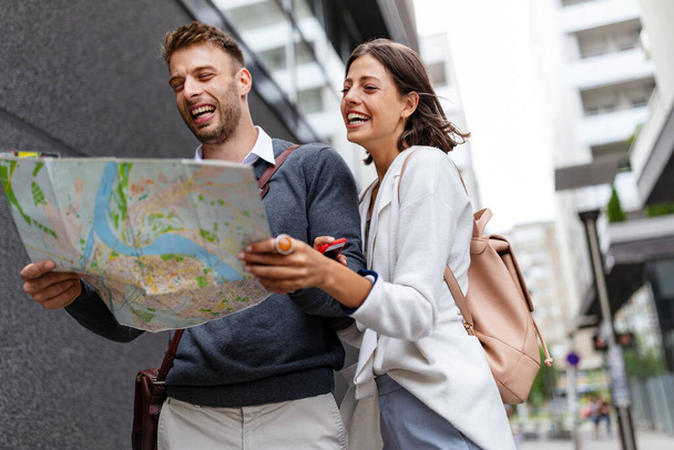 Holidays, dating and tourism concept. Smiling beautiful couple in love with map in the city - Zdjęcie, obraz