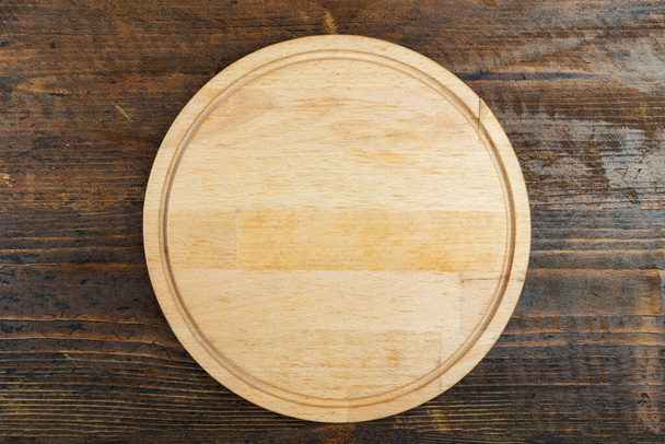 Round cutting board on a wooden table. Space for text. Top View. - Fotó, kép