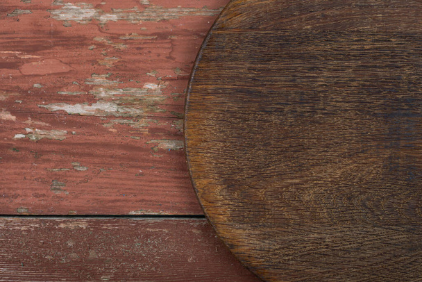 Circle cutting board on a red wooden table. Food preparation tool and kitchen utensils. Space for text. - Foto, Bild