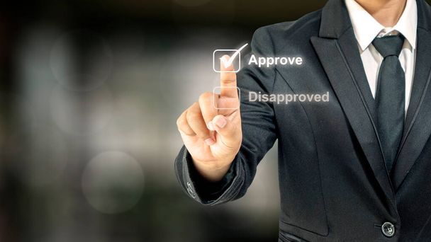 Close-up of human hand-selecting checkbox labeled approved over blurred background financial statement approval concept. Investment loan - Photo, Image