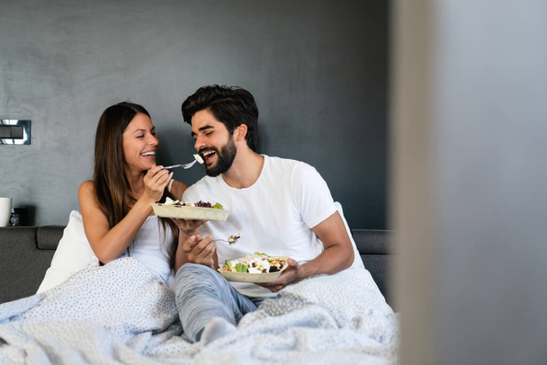 Healthy breakfast in bed. Young beautiful love couple is sitting in bed and having breakfast. - Φωτογραφία, εικόνα