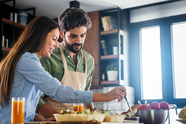 Happy young couple cooking together in the kitchen at home - Foto, imagen