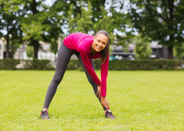smiling black woman stretching leg outdoors - Fotoğraf, Görsel
