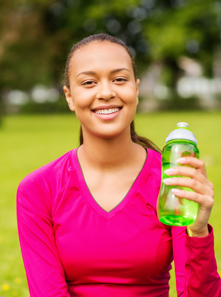 улыбающаяся девушка-подросток, показывающая бутылку
 - Фото, изображение