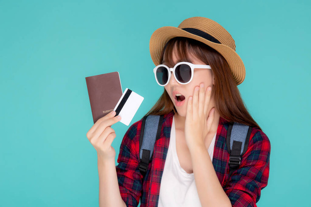 schöne junge asiatische Frau aufgeregt und überrascht mit Kreditkarte und Reisepass zu reisen Sommerreise isoliert auf blauem Hintergrund, Mädchen Ausdruck schockiert Reise im Urlaub. - Foto, Bild