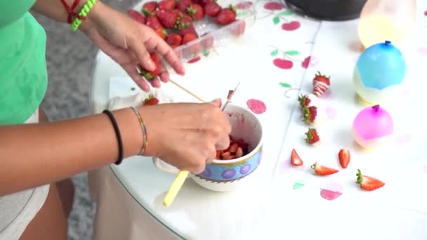 Kreatywny dzień gotowania: kobieta kroi truskawki, aby ugotować deser z owocami i czekoladą w domu. - Materiał filmowy, wideo