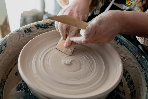 el proceso de alfarero hecho a mano en la ropa tradicional de los eslavos. nivelación de un plato de arcilla en la rueda de un alfarero - Foto, Imagen
