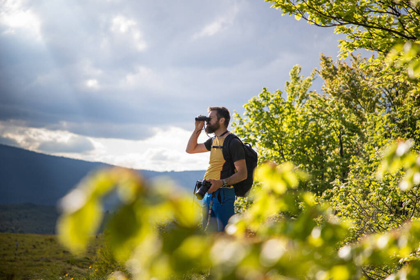 schöner Mann beim Trekking in der Natur mit Ferngläsern - Foto, Bild