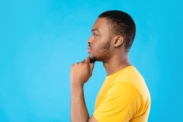 Side View Portrait Of Thoughtful Black Guy On Blue Background - 写真・画像