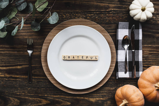 Thanksgiving place setting with plate, napkin, on a  decorated table shot from flat lay or top view position. Grateful spelled out with wood block letters. - Photo, Image