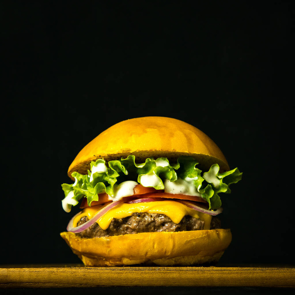 Sabrosa hamburguesa gourmet casera fresca en mesa de madera con fondo oscuro - Foto, Imagen