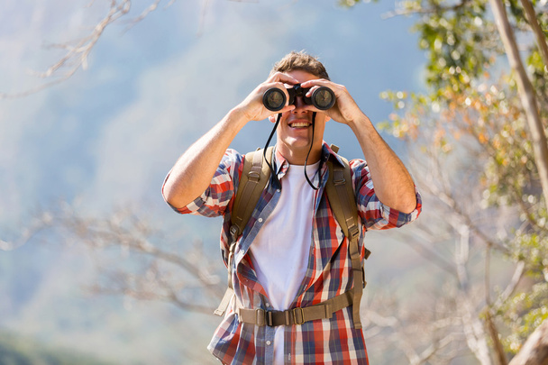 Hiker using binoculars on top of mountain - Фото, изображение