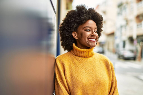Joven afroamericana americana sonriendo feliz de pie en la ciudad. - Foto, imagen