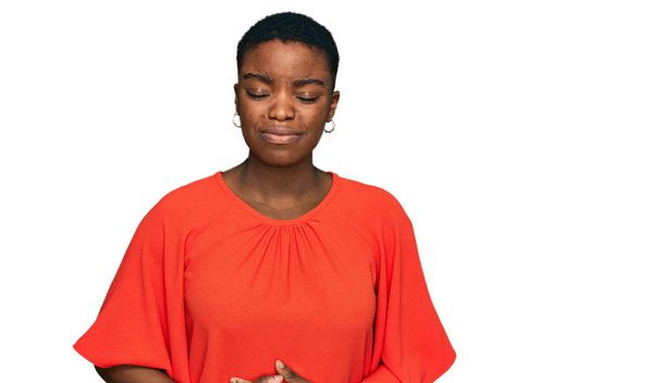 Giovane donna afroamericana che indossa abiti casual con mano sullo stomaco perché indigestione, malattia dolorosa sensazione di malessere. concetto di dolore.  - Foto, immagini