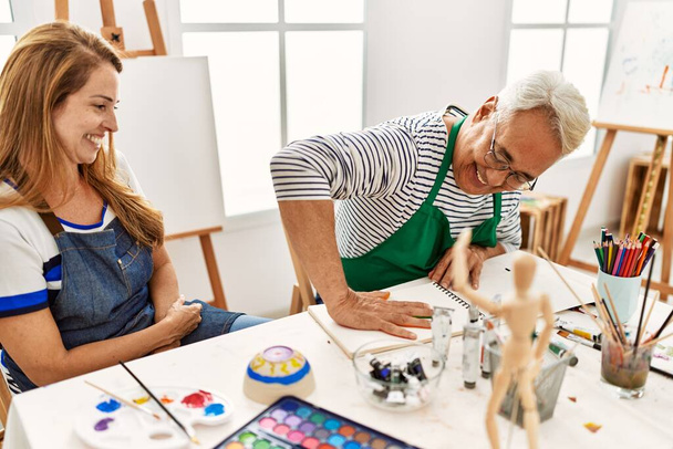 Двоє художників середнього віку посміхаються щасливим живописом з розфарбованими руками на ноутбуці в художній студії
. - Фото, зображення