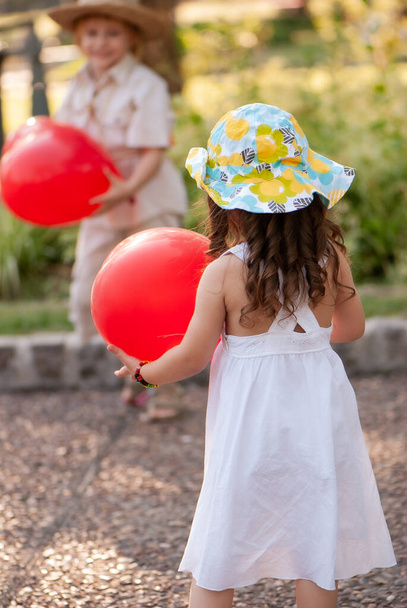Little happy girl in a white dress with an ball in the park - Photo, image