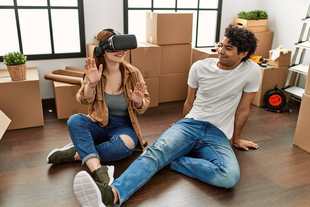 Young couple smiling happy playing with 3d vr glasses at new home. - 写真・画像