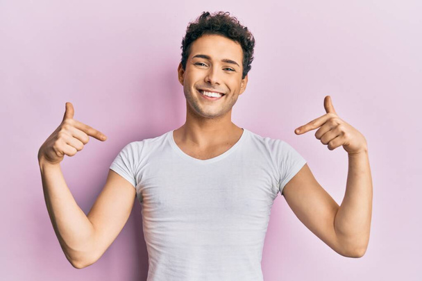 Young handsome man wearing casual white t shirt looking confident with smile on face, pointing oneself with fingers proud and happy.  - Photo, Image