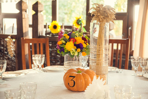 Ünnepi virágzás őszi stílusban, asztalszámozással a sütőtökre a bankett teremben. Rendezvények virágdísze és díszítése. - Fotó, kép