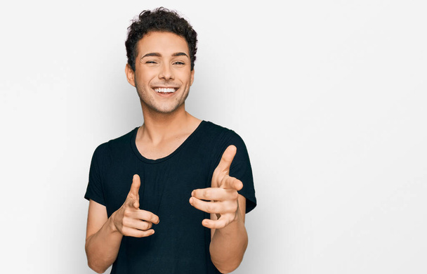 Young handsome man wearing casual black t shirt pointing fingers to camera with happy and funny face. good energy and vibes.  - Photo, Image
