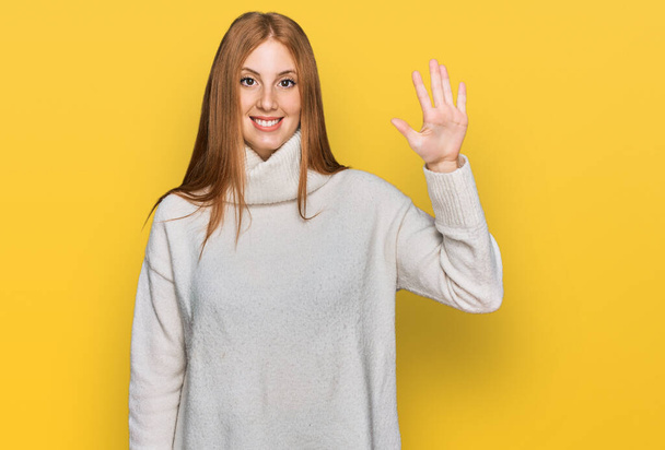 Młoda Irlandka ubrana w luźny zimowy sweter pokazująca i wskazująca palcami numer pięć uśmiechnięta pewna siebie i szczęśliwa.  - Zdjęcie, obraz