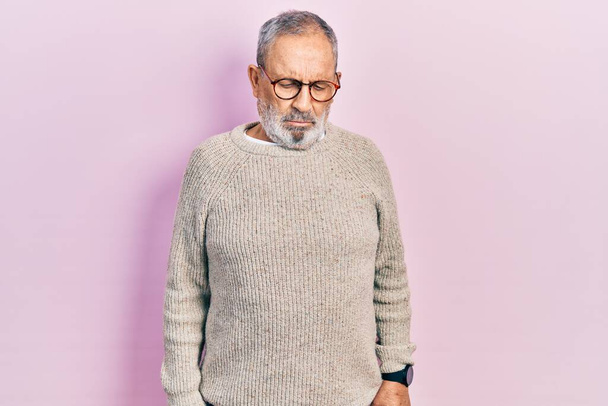Handsome senior man with beard wearing casual sweater and glasses depressed and worry for distress, crying angry and afraid. sad expression.  - Fotografie, Obrázek