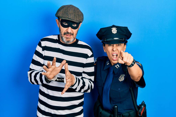 Orta yaşlı bir çift İspanyol kadın ve hırsız ve polis üniforması giyen adam kameraya kızgın ve sinirli bir şekilde bakıyor.  - Fotoğraf, Görsel