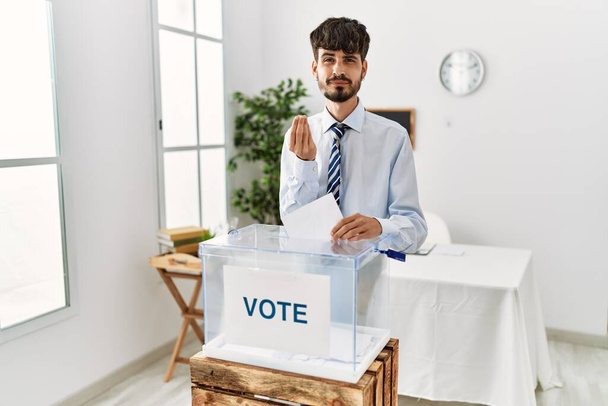 Hispánec s plnovousem, který hlasuje, dává obálku do volební urny, dělá gesto peněz rukama, žádá výplatu, milionářský byznys  - Fotografie, Obrázek