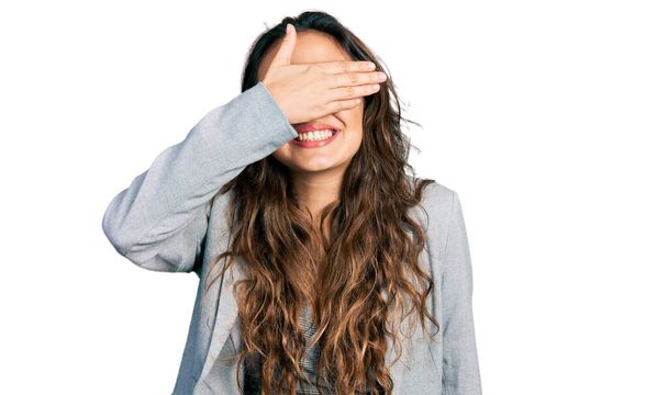 Menina hispânica jovem vestindo roupas de negócios e óculos sorrindo e rindo com a mão no rosto cobrindo os olhos para surpresa. conceito cego.  - Foto, Imagem