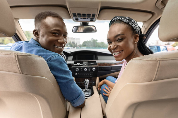 Happy afro american couple posing in auto, looking at backseat - Photo, Image