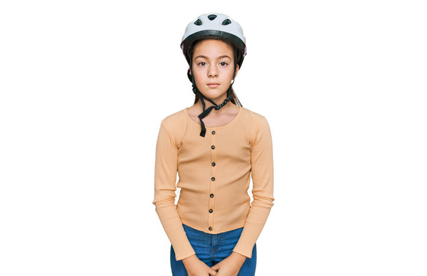 Belle petite fille brune portant un casque de vélo avec une expression sérieuse sur le visage. simple et naturel regardant la caméra.  - Photo, image