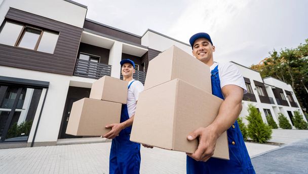 Two removal company workers unloading boxes into new customers home - Fotoğraf, Görsel