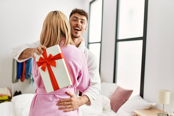 Jeune couple caucasien souriant heureux surprenant avec chambre cadeau anniversaire. - Photo, image