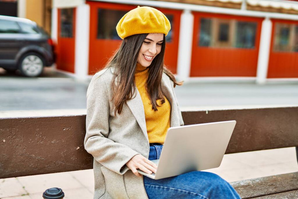 Young hispanic girl smiling happy working using laptop at the city. - 写真・画像