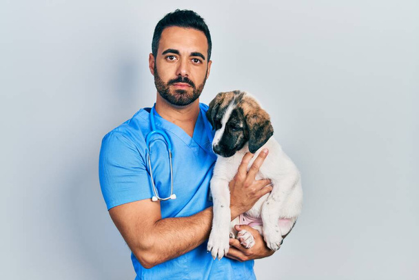 Красивый латиноамериканец-ветеринар с бородой, проверяющий здоровье собаки, расслабленный с серьезным выражением лица. простой и естественный взгляд на камеру.  - Фото, изображение