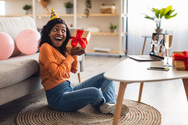 Musta nainen vastaanottaa lahja ottaa Online syntymäpäiväjuhlat kotona - Valokuva, kuva