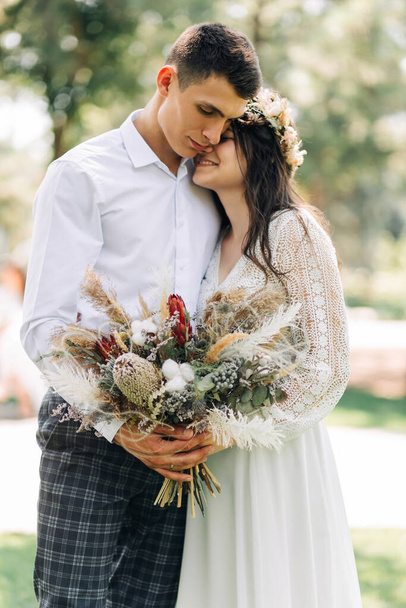 Happy family of bride and groom, Smiling newlyweds together in wedding suits, in the park on a sunny day, Concept of love and happiness, wedding day, wedding ceremony in boho style - Foto, Imagem