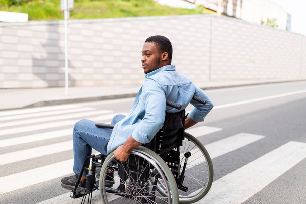 Lebensqualität und Beeinträchtigung Millennial querschnittsgelähmter schwarzer Mann im Rollstuhl nutzt im Herbst Fußgängerüberweg im Freien - Foto, Bild