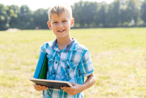 Мальчик держит планшет PC на зеленой газоне травы с копировальным местом
. - Фото, изображение