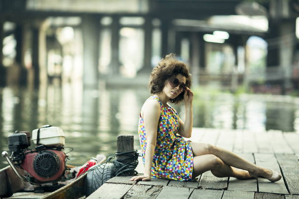 Eine junge Asiatin sitzt auf einem Flusssteg. - Foto, Bild