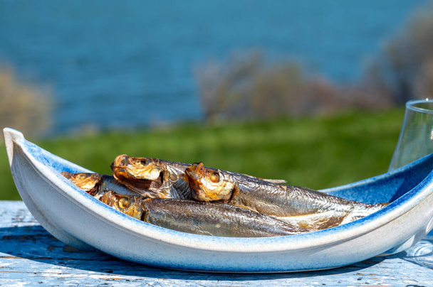 Копчений спрат або спритч морська риба, що подається на відкритому повітрі з видом на блакитну морську воду, готова до їжі
 - Фото, зображення