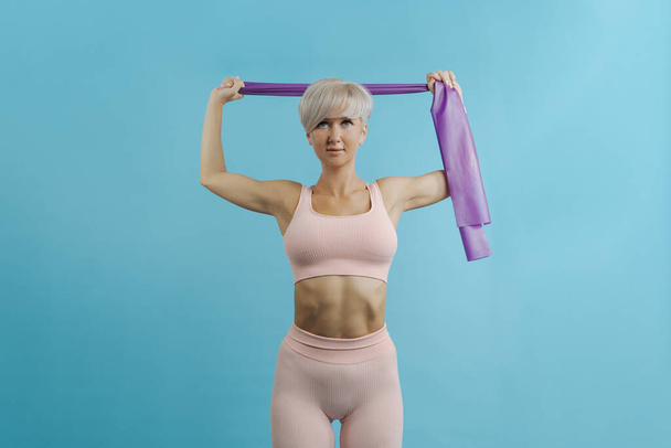 Beautiful sportive woman doing exercises with rubber bands. COPY SPACE. - Photo, image
