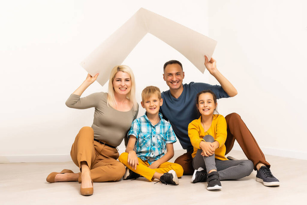 concept housing a young family. family with roof on white background - Фото, изображение