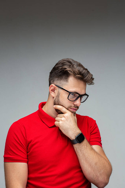 Serious pensive young man businessman in glasses thinking, solving problems, studio portrait on gray with copy space - Φωτογραφία, εικόνα