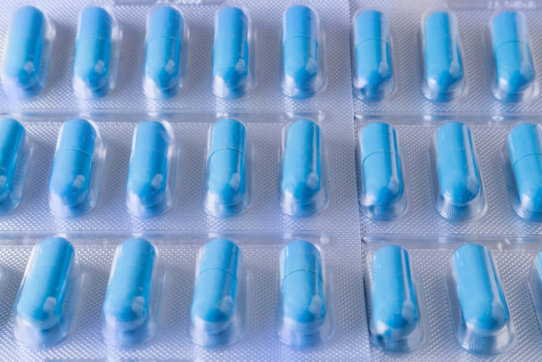 Tło opakowanych niebieskich kapsułek medycznych. Produkcja leków i witamin - Zdjęcie, obraz