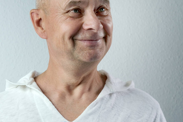 close-up face of a middle-aged man, a senior in white looks, smiles, the concept of emotions of the elderly, happiness, laughter prolongs life - Fotografie, Obrázek