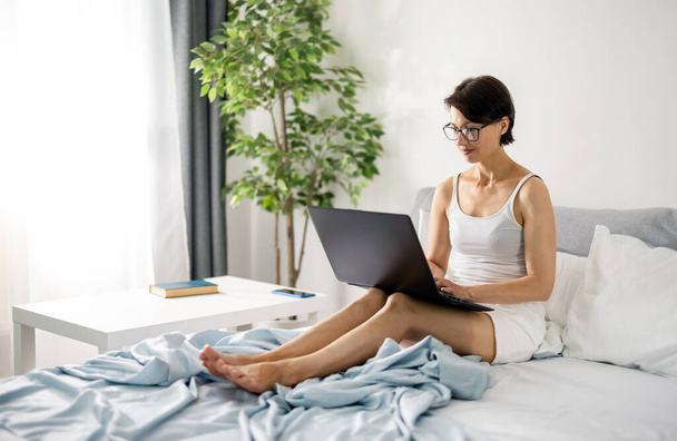 Freelancer with laptop in bed - 写真・画像